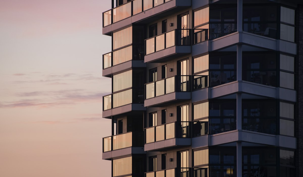 Modern apartment building with glass balconies at dusk